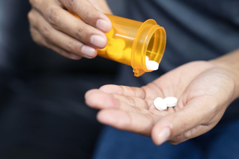 Hands holding an opioid pill bottle