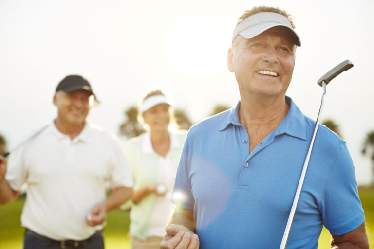 Senior age man finishing a golf put with friends